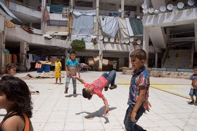 Các em nhỏ người Syria chơi đùa trong sân một khu lưu trú ở Jordan.