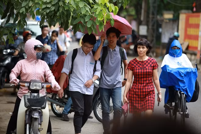 Các bạn học sinh che ô tránh mưa nhỏ bước vào điểm thi tại Hà Nội.