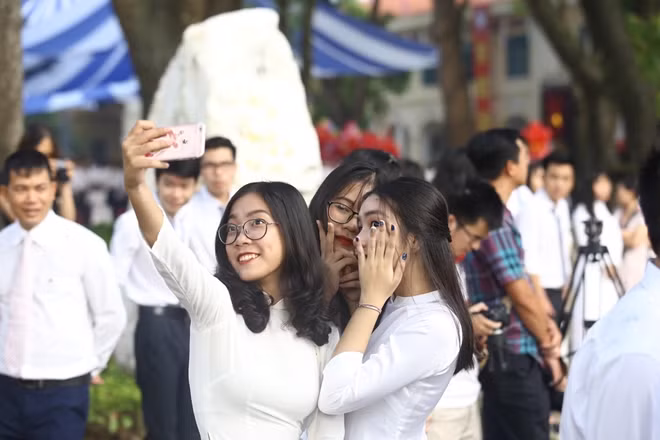 Các bạn nữ tranh thủ chụp ảnh selfie trước khi lễ khai giảng bắt đầu. Bạn Thúy An, một học sinh lớp 11, cho biết rất nhớ bạn bè sau những ngày nghỉ hè và tranh thủ cơ hội được mặc áo dài để lưu lại những kỉ niệm đẹp.