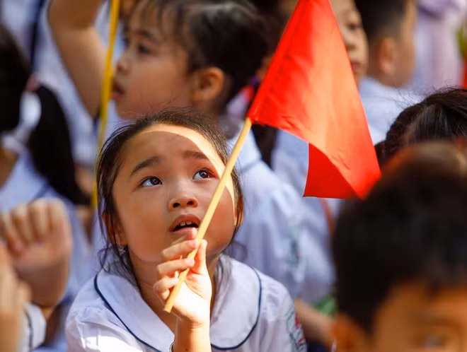 Một bạn học sinh khéo léo lấy cờ để ... che nắng tại lễ khai giảng.