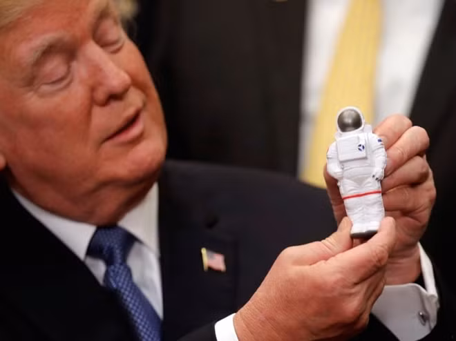 Tổng thống Mỹ Donald Trump cầm mô hình bộ quần áo phi hành gia khi nói về kế hoạch chinh phục không gian cách đây không lâu. Ảnh: Reuters