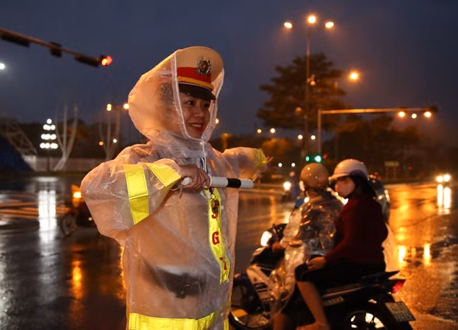 Một nữ chiến sĩ CSGT điều tiết giao thông tại nút giao gần Trung tâm Báo chí trong mưa lớn và gió giật mạnh.
