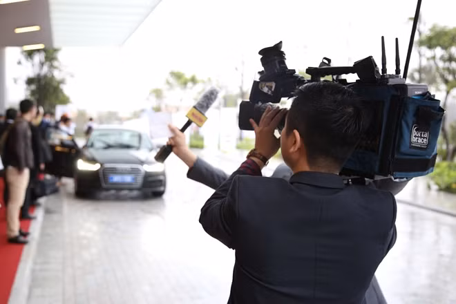 Hai phóng viên tác nghiệp dưới mưa tại một trung tâm hội nghị APEC.