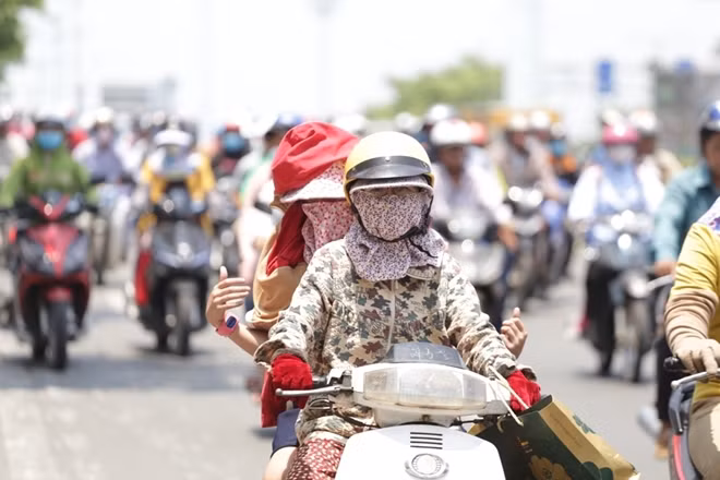 Những người phụ nữ ra đường trong trang phục kín mít để tránh nóng ở Việt Nam.