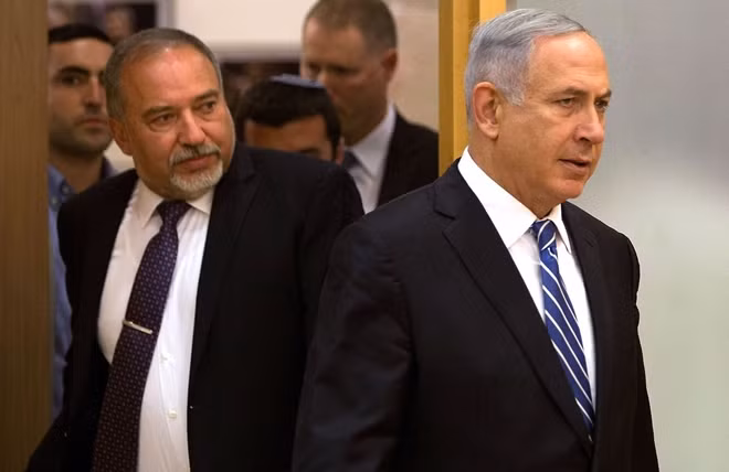 Ông Netanyahu bước ra khỏi phòng họp, theo sau là cựu Bộ trưởng Quốc phòng Lieberman. Ảnh: Reuters
