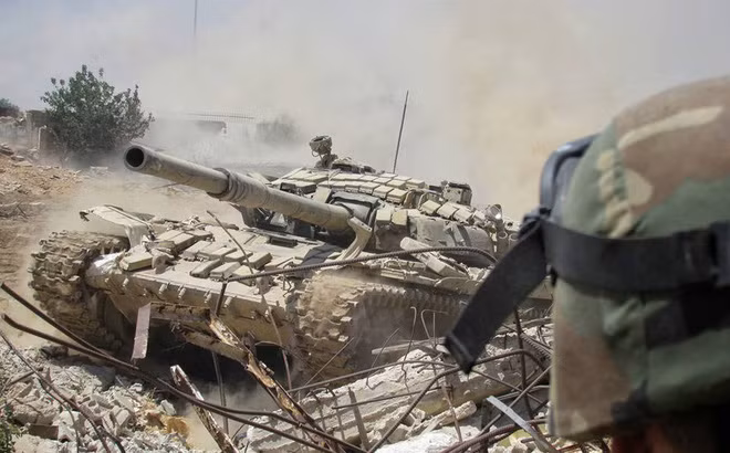 Một chiếc xe tăng của quân đội Syria di chuyển qua đống đổ nát. Ảnh: ITN Một chiếc xe tăng của quân đội Syria di chuyển qua đống đổ nát. Ảnh: ITN