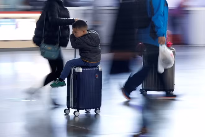 Một cậu bé đang cùng mẹ vội vã trên đường ra máy bay về quê đón Tết. Ảnh: Reuters