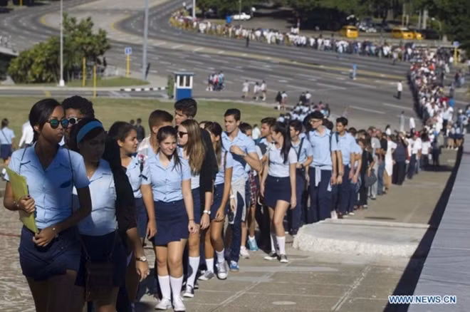 Trong dòng người xếp hàng vào viếng Fidel có rất nhiều các thế hệ học sinh, sinh viên Cuba, họ giơ cao cờ Cuba và hô vang các khẩu hiệu: “Viva Fidel”, “Viva Raul”. Ảnh: Tân Hoa Xã