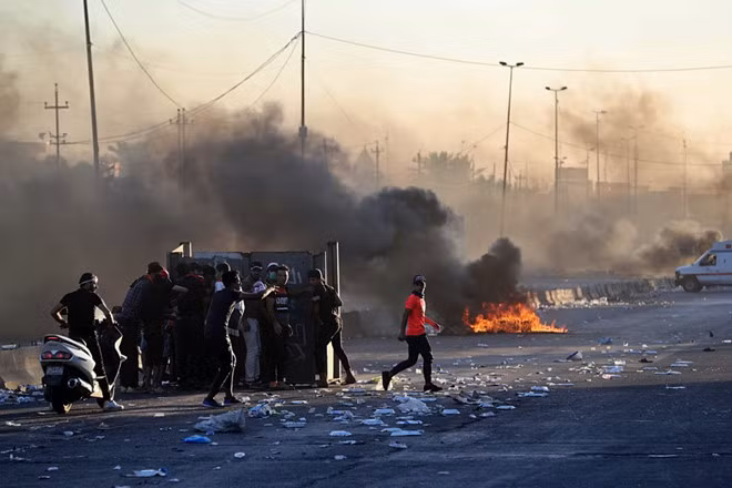 Người biểu tình Iraq đứng sau tấm ván sắt trên cao tốc ở Baghdad. Ảnh: Getty Images