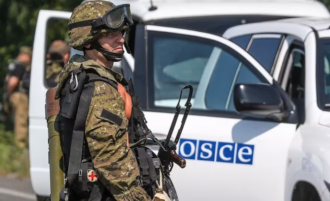 Một quân nhân đứng cạnh xe của tổ chức OSCE ở Ukraine. Ảnh: RT