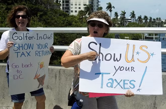 Một người phụ nữ tuần hành phản đối Trump gần khu nghỉ dưỡng Mar-a-Lago yêu cầu ông phải trở về Washington để làm việc của mình và đặt ra câu hỏi với Trump: “Ngài là tổng tư lệnh của các tay golf”. Ảnh: Reuters.