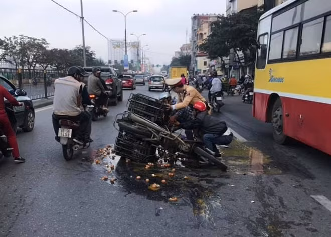 Chiến sĩ CSGT giúp người đàn ông dựng xe và dọn dẹp số trứng rơi vỡ.