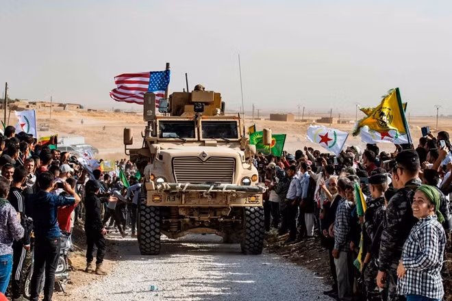 Người Kurd đứng vây quanh một xe bọc thép của Mỹ gần biên giới Thổ Nhĩ Kỳ-Syria. Ảnh: Reuters