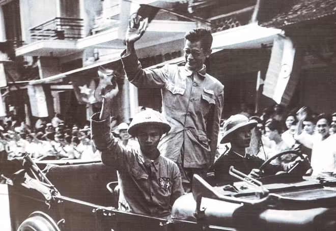Bác sĩ Trần Duy Hưng, người cũng đồng thời là Phó Chủ tịch Uỷ ban Quân chính Hà Nội, vẫy chào người dân Thủ đô trên phố Hàng Đào.