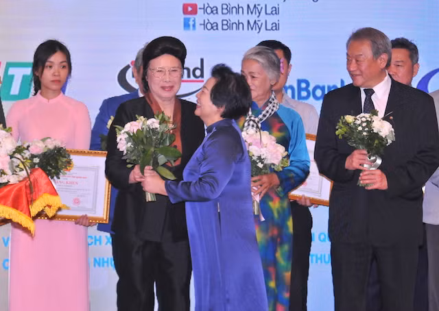 Chủ tịch Hội đồng quản lý Quỹ Hòa Bình Mỹ Lai – bà Trương Ngọc Thủy trao hoa, cảm ơn những đóng góp tích cực của GS-TS Phan Lương Cầm, phu nhân Cố Thủ tướng Võ Văn Kiệt, đối với Quỹ.