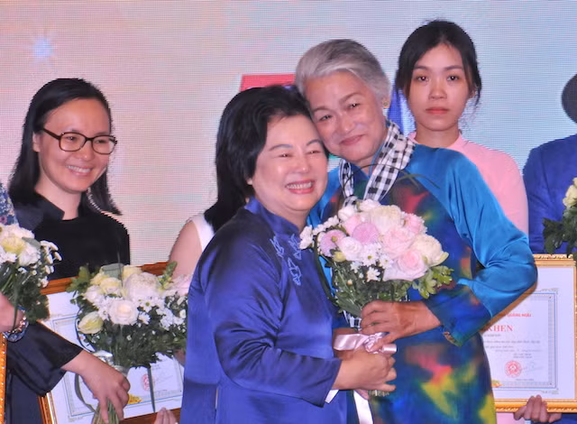 Chủ tịch Hội đồng quản lý Quỹ Hòa Bình Mỹ Lai – bà Trương Ngọc Thủy trao hoa, cảm ơn Họa sĩ Đặng Ái Việt.