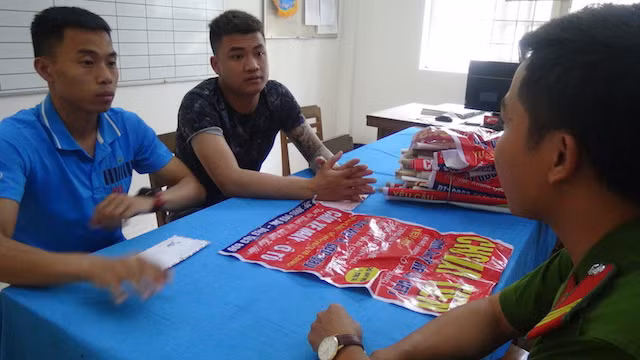 Hai thanh niên dán quảng cáo trái phép được mời về trụ sở Công an làm việc.