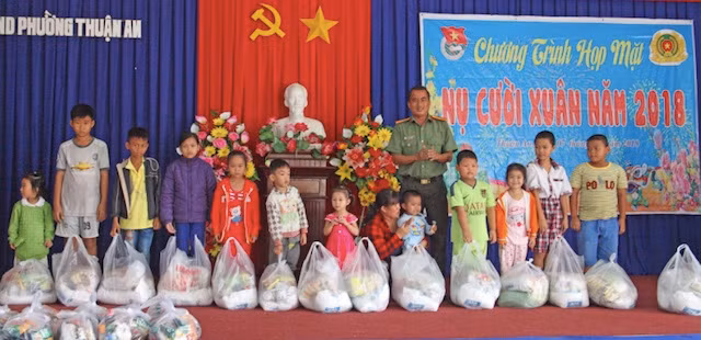 Thiếu tá Lê Việt Trung, Phó Phòng Công tác chính trị trao quà cho các em nhỏ.