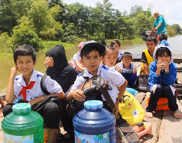 Các em học sinh đầu nguồn vùng lũ di chuyển đến trường bằng đò.
