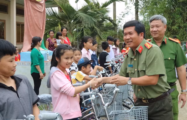 Đại tá Đinh Văn Nơi trao quà cho các em học sinh.