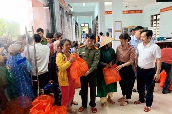 Đại tá Phạm Khải, Tổng biên tập Báo CAND cùng đại diện nhà tài trợ trao quà cho bà con xã Vinh Hiền.