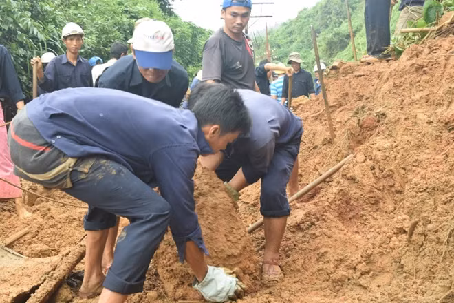 Công nhân đường sắt khuân vác những khối đá rơi từ trên núi xuống chắn ngang đường ray.