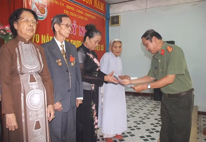 Trung tá Nguyễn Văn Long, Phó Ban Thư ký Tòa soạn, Trưởng VPTT Báo CAND tại miền Trung trao quà cho các gia đình chính sách, thân nhân thờ phụng liệt sĩ ở thị trấn Lăng Cô.