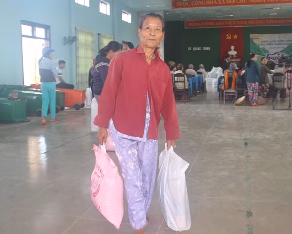 Niềm vui khi được nhận quà hỗ trợ sau cơn lũ của một phụ nữ ở thôn Tân Thành, xã Quảng Thành.