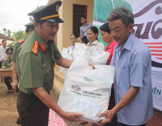 Trung tá Nguyễn Văn Long, Trưởng VPTT Báo CAND tại miền Trung trao tặng những phần quà đến người dân xã Vĩnh Trung.