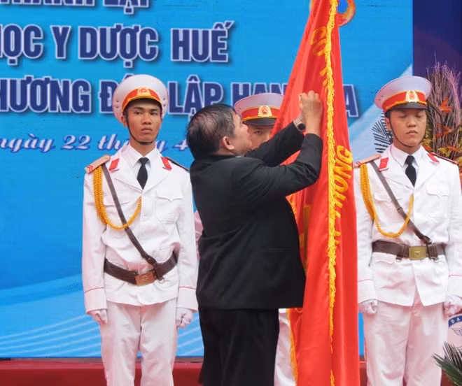 Thứ trưởng Bộ GD&ĐT Bùi Văn Ga gắn Huân chương Độc lập hạng Ba lên lá cờ truyền thống của nhà trường.