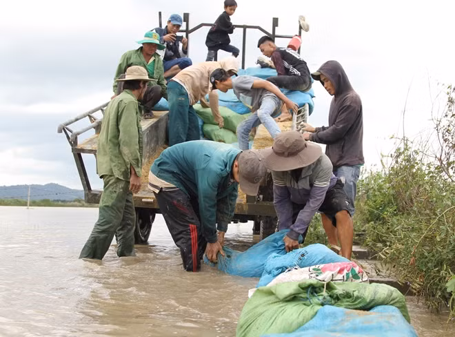 Đến chiều 12-8, hàng trăm người dân và phương tiện vẫn đang cố gắng gia cố bờ kênh để chặn nước