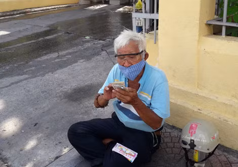 Ông Ngàn, 78 tuổi, ngồi trước chùa Lâm Tế, đường Nguyễn Trãi, quận 1, bán những tờ vé số cuối cùng trước khi vé số tạm dừng phát hành.