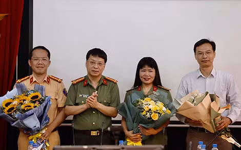 Đại tá Phạm Khải - Tổng Biên tập Báo Công an nhân dân (thứ hai, từ trái sang) tặng hoa cho các diễn giả tham gia giao lưu trực tuyến.