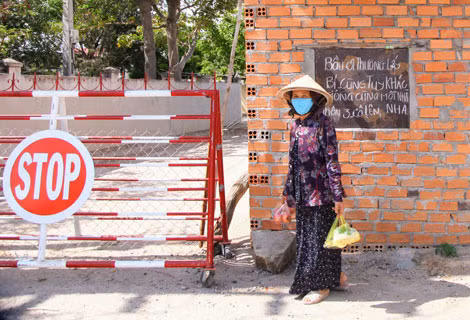 Người phụ nữ trước tấm bảng kêu gọi đoàn kết, chia sẻ.