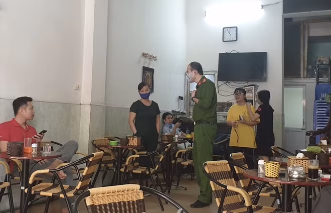 Cán bộ Công an nhắc nhở người dân kinh doanh cà phê chấp hành yêu cầu tạm đóng cửa của thành phố Hà Nội.