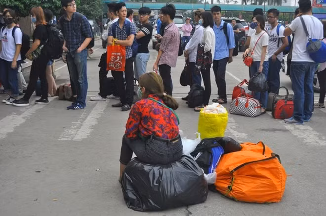 Hành khách ngồi vật vờ xếp hàng.