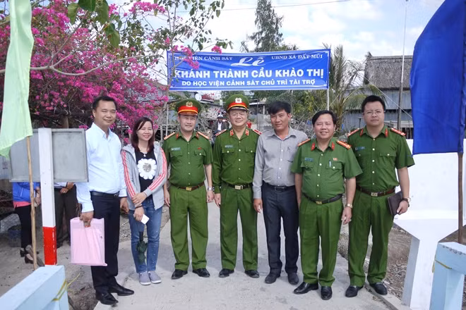 Đại diện Ban giám hiệu Học viện CSND, nhân dân và các em học sinh bên cây cầu vừa khánh thành.