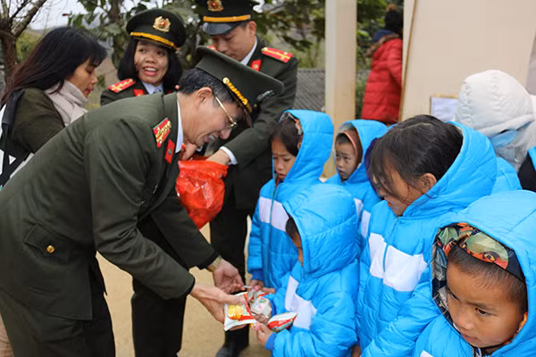 Đại tá Hoàng Văn Toàn trao quà cho các em học sinh.