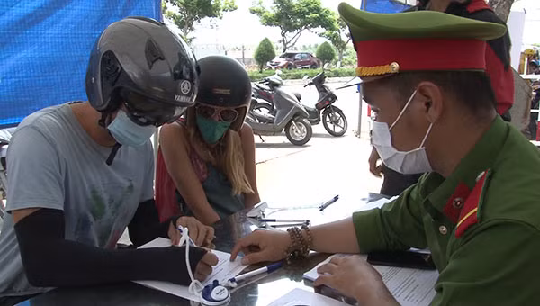 Cán bộ, chiến sĩ Công an hướng dẫn người nước ngoài kê khai y tế tại chốt kiểm dịch.