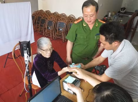 Trung tá Lê Lâm Phong cùng cán bộ Đội QLHC về TTXH, Công an quận Thanh Xuân làm CMND tại nhà cho bà Nguyễn Thị Mùi.