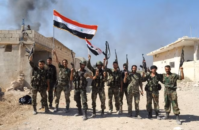 Binh lính với lá cờ Syria trên mảnh đất vừa giành lại từ tay IS. Ảnh Getty