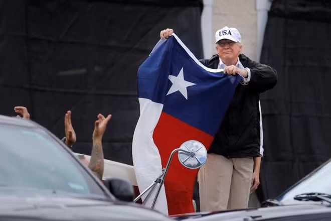Tổng thống Donald Trump dương lá cờ của bang Texas ngay trước khi dự một cuộc họp tại một trạm cứu hỏa ở thành phố Corpus Christi, nơi đang có rất nhiều người dân đón chờ Tổng thống
