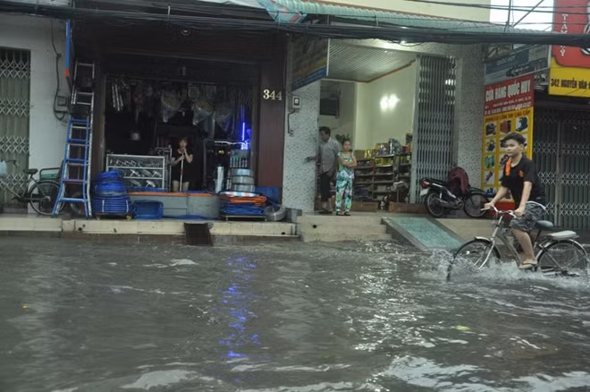 Nhiều chủ cửa hàng buôn bán ngán ngẫm nhìn nước dâng trên đường