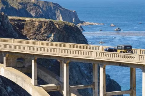 Chiếc xe cổ đang đi qua cầu Bixby ở Big Sur, California.