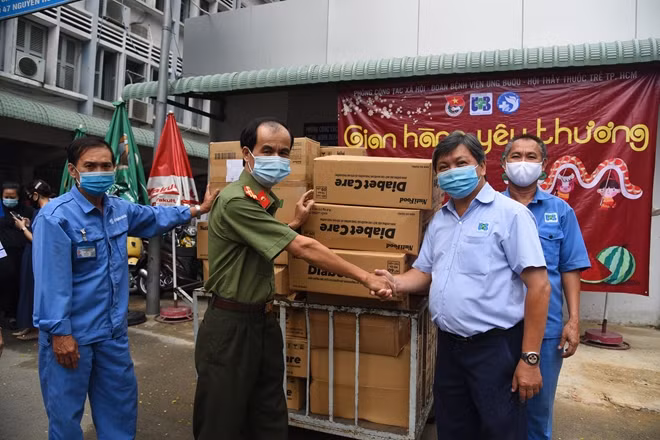 Thượng tá Nguyễn Đức Vinh trao 400 hộp sữa Nutifood cho ông Nguyễn Thành Sơn, phụ trách tổ từ thiện - phòng Công tác xã hội Bệnh viện Ung bướu TP Hồ Chí Minh.