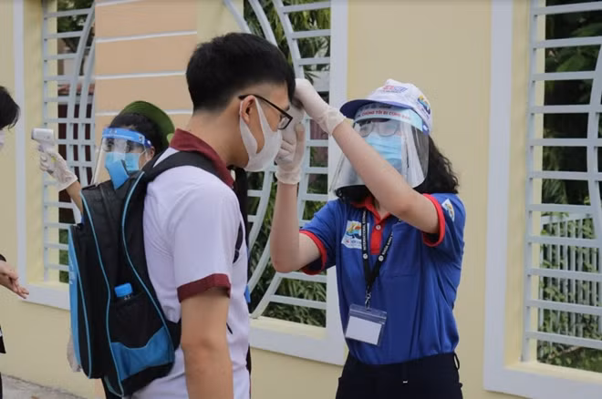 Thí sinh được tình nguyện viên đo thân nhiệt tại điểm thi THPT NGuyễn Hữu Huân-TP Thủ Đức.