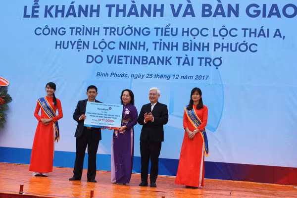 Đại diện lãnh đạo VietinBank (bên trái) trao bảng tượng trưng số tiền 10 tỉ đồng cho lãnh đạo huyện Lộc Ninh.