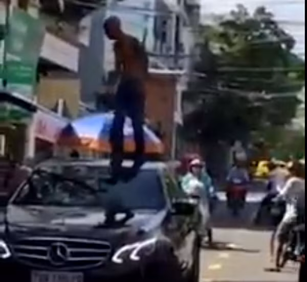 Kẻ “ngáo đá” Nguyễn Thanh Sơn đang múa may, la hét khi đứng trên mui xe ô tô Mercedes. Ảnh cắt từ clip của người dân.