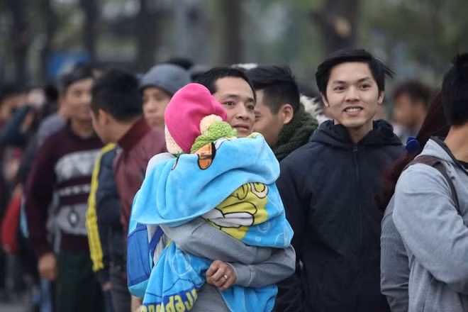 Ông bố này đưa theo cả con trai đi cùng để xếp hàng chờ mua vé. Anh khoác một tấm chăn dày và mặc rất ấm cho cháu bé để chống cái lạnh, sương giá vào sáng sớm.