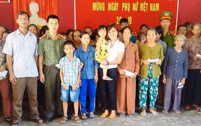 Đoàn công tác xã hội từ thiện Báo CAND và Công ty Duy Lợi trao quà, chụp ảnh lưu niệm với bà con vùng lũ xã Hàm Ninh, huyện Quảng Ninh, Quảng Bình.